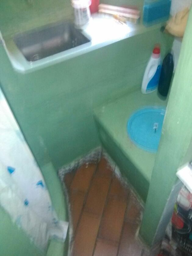 A la derecha, sobre la tapa metálica azul, se encuentra la letrina donde ambos presos deben hacer sus necesidades; al frente, un lavabo; a la izquierda, la ducha.