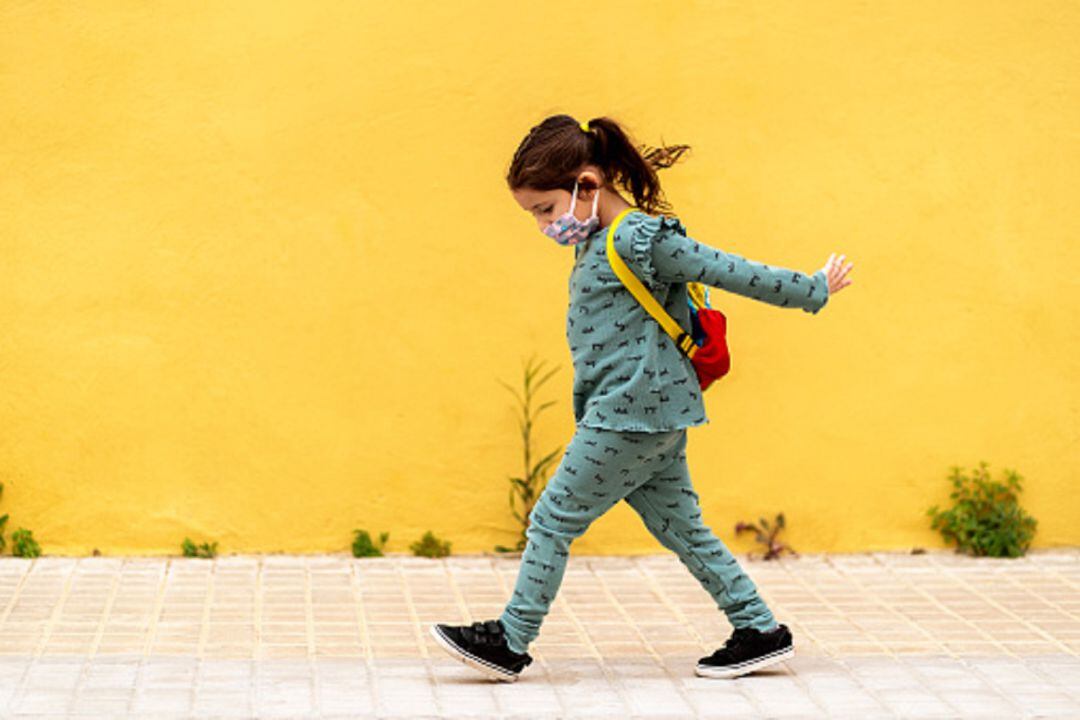 Niña con mascarilla caminando 