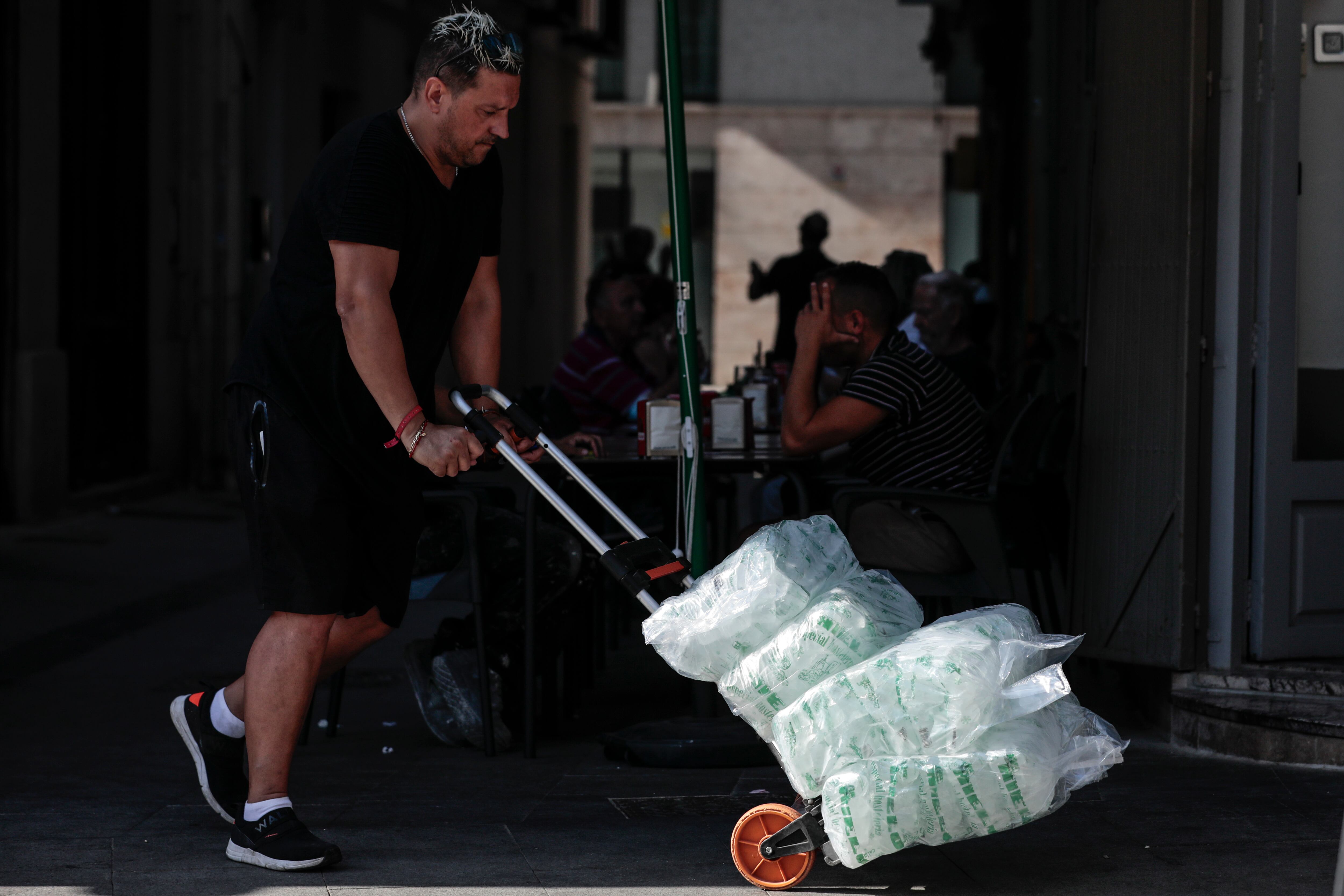 Un repartidor lleva una carretilla cargada con bolsas de hielo a un bar en València, en una imagen de archivo.
