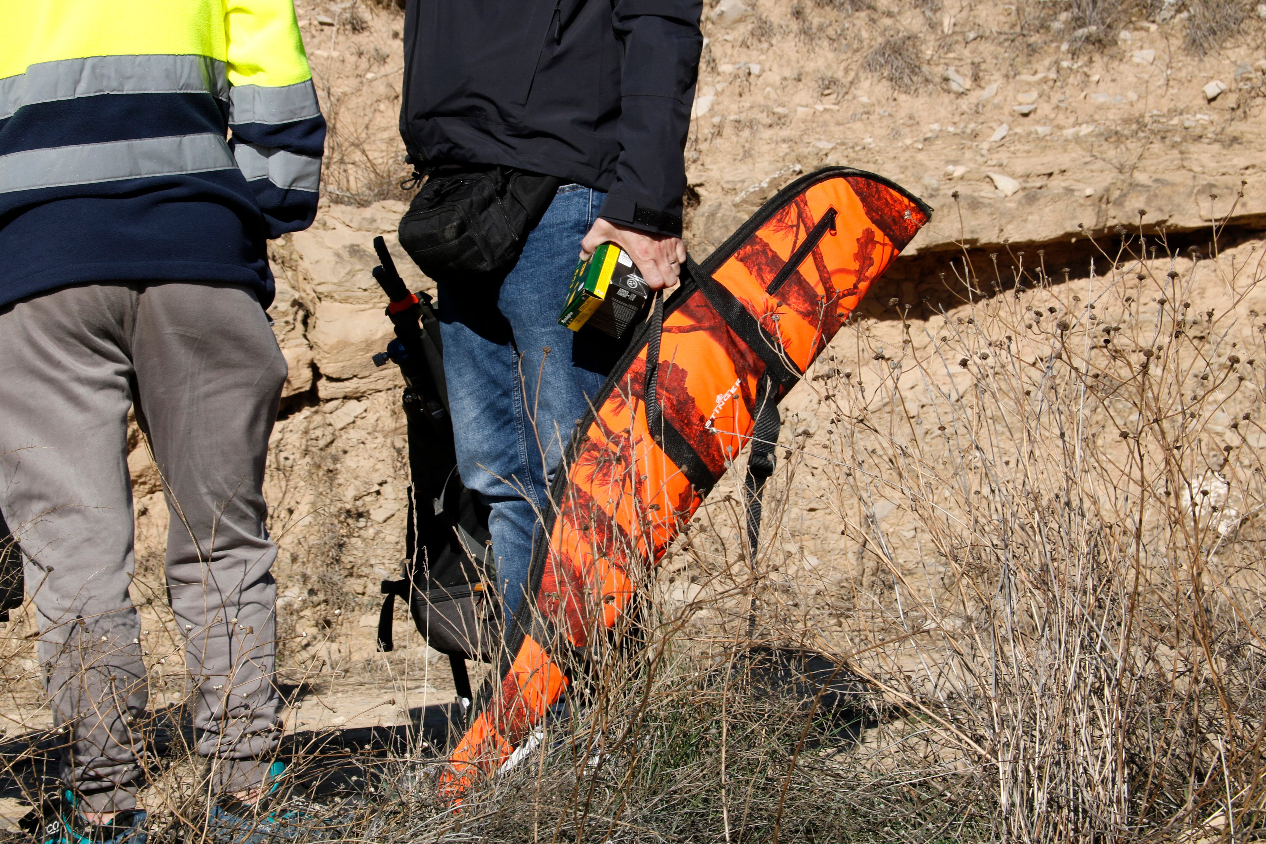 Un policia porta una arma i munició al lloc on un caçador ha resultat mort pel tret d'un altre. Foto: ACN.
