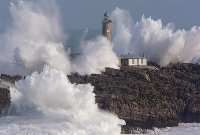 El faro de la isla de Mouro, situado en la bocana del Puerto de Santander, es batido fuertemente por el oleaje esta mañana, donde se ha continuado sufriendo los efectos del temporal de viento y olas que afecta a la costa cantábrica.