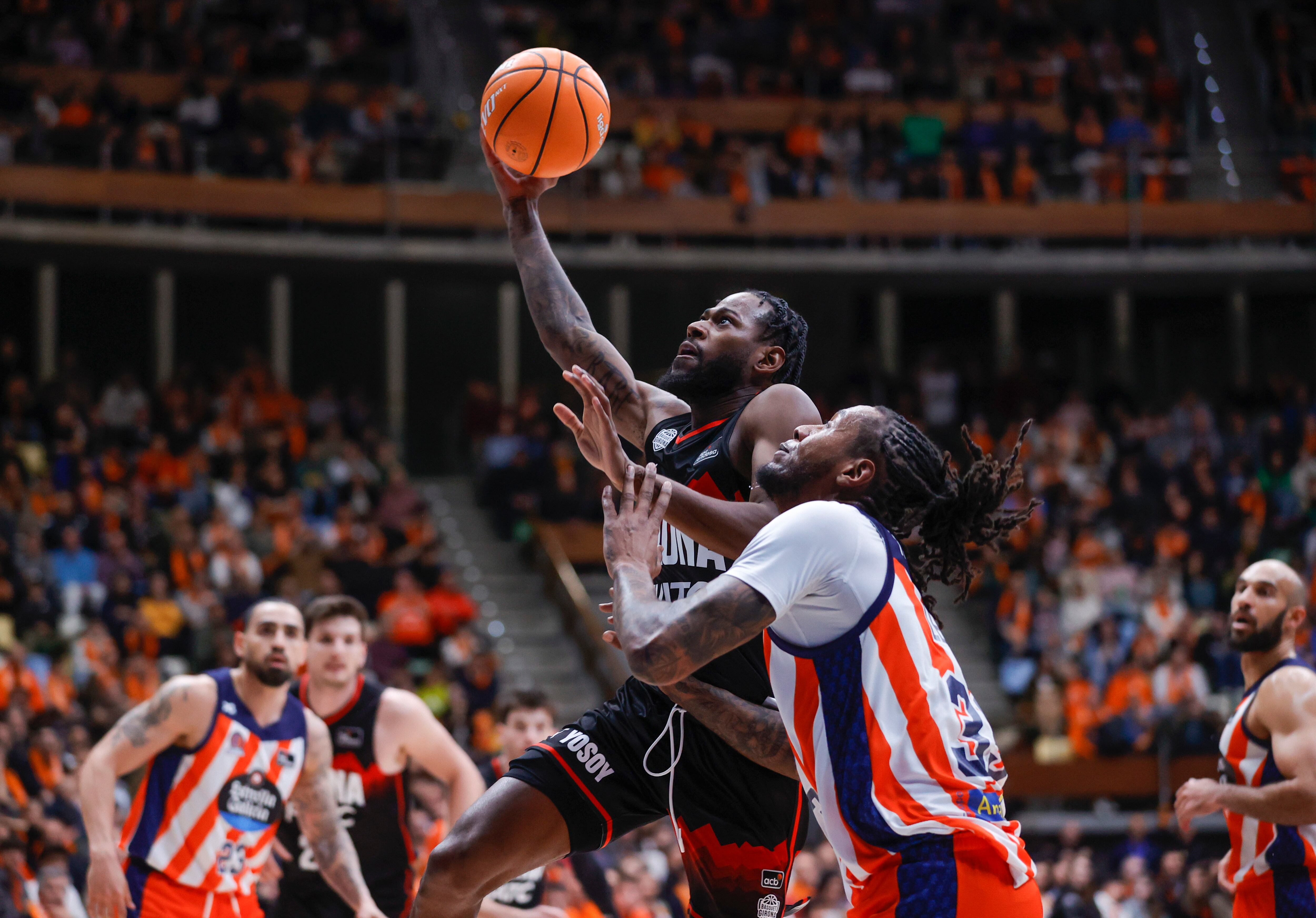 LA CORUÑA, 29/03/2025.- El base estadounidense del Básquet Girona, Aljami Durham (i) entra a canasta ante el ala-pívot estadounidense del Leyma Básquet Coruña, Trey Thompkins, durante el partido de la jornada 25 de la Liga Endesa que Leyma Básquet Coruña y Básquet Girona juegan este sábado en el Coliseum de A Coruña.- EFE/ Cabalar