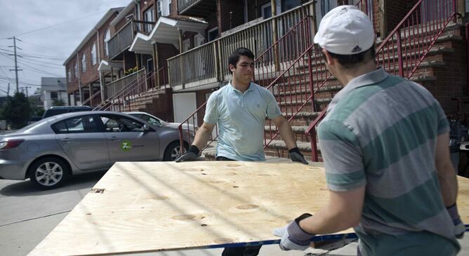 Dos jóvenes se disponen a tapar sus ventanas en Rockaway Beach, Nueva York, ante la llegada del huracán Irene