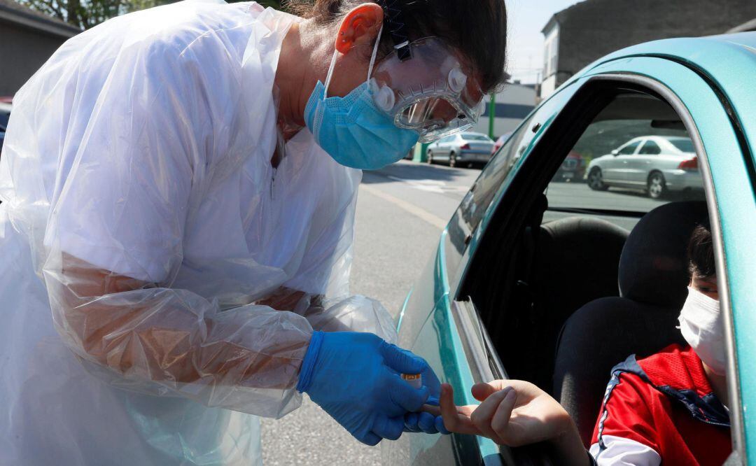 Personal sanitario realiza un test de coronavirus a una persona que va en coche.
