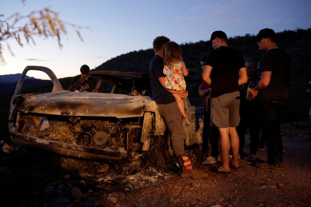 Miembros de la comunidad mormona observan el coche calcinado de la familia LeBarón.