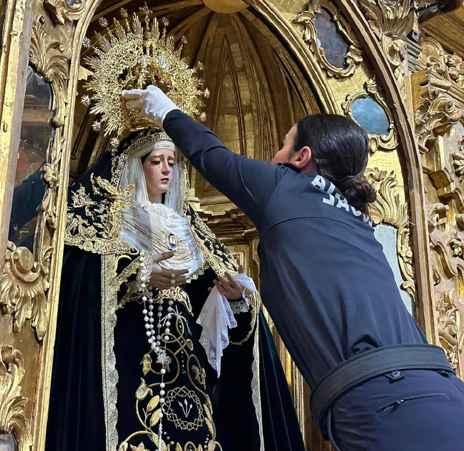 Una agente de la Policía Local de Baeza coloca la corona a Nuestra Señora de la Soledad.