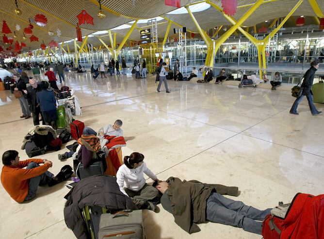 Cientos de personas esperan la salida de sus vuelos en una terminal del aeropuerto de Madrid-Barajas, cuyo cierre provocado por el abandono masivo de sus puestos de trabajo de los controladores aéreos ha afectado ya a decenas de miles de viajeros