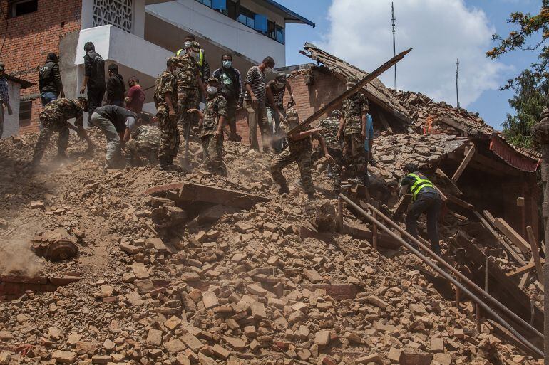 Un grupo de militares y voluntarios retiran escombros de varios edificios en Katmandú tras sufrir un fuerte terremoto