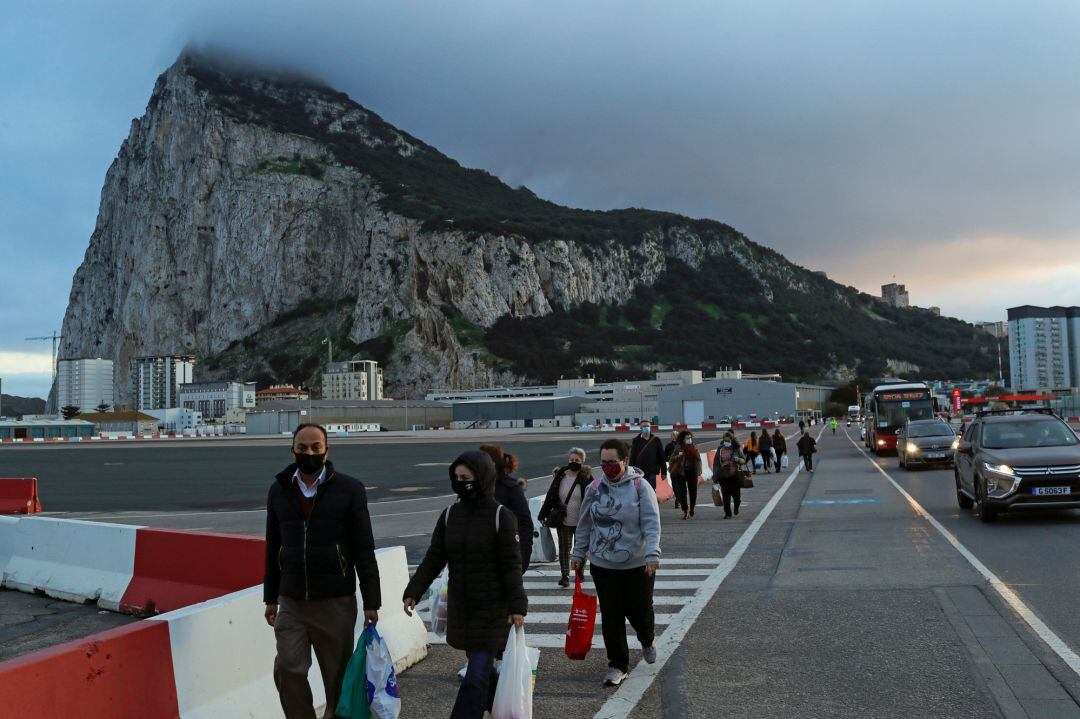 Varios pasajeros cruzan la pista del Aeropuerto Internacional de Gibraltar hacia España, después de que el gobierno español anunciara que prohibirá la entrada a todos los viajeros de Gran Bretaña a partir del martes tras detectarse una nueva cepa de Covid-19 que se está extendiendo rápidamente.