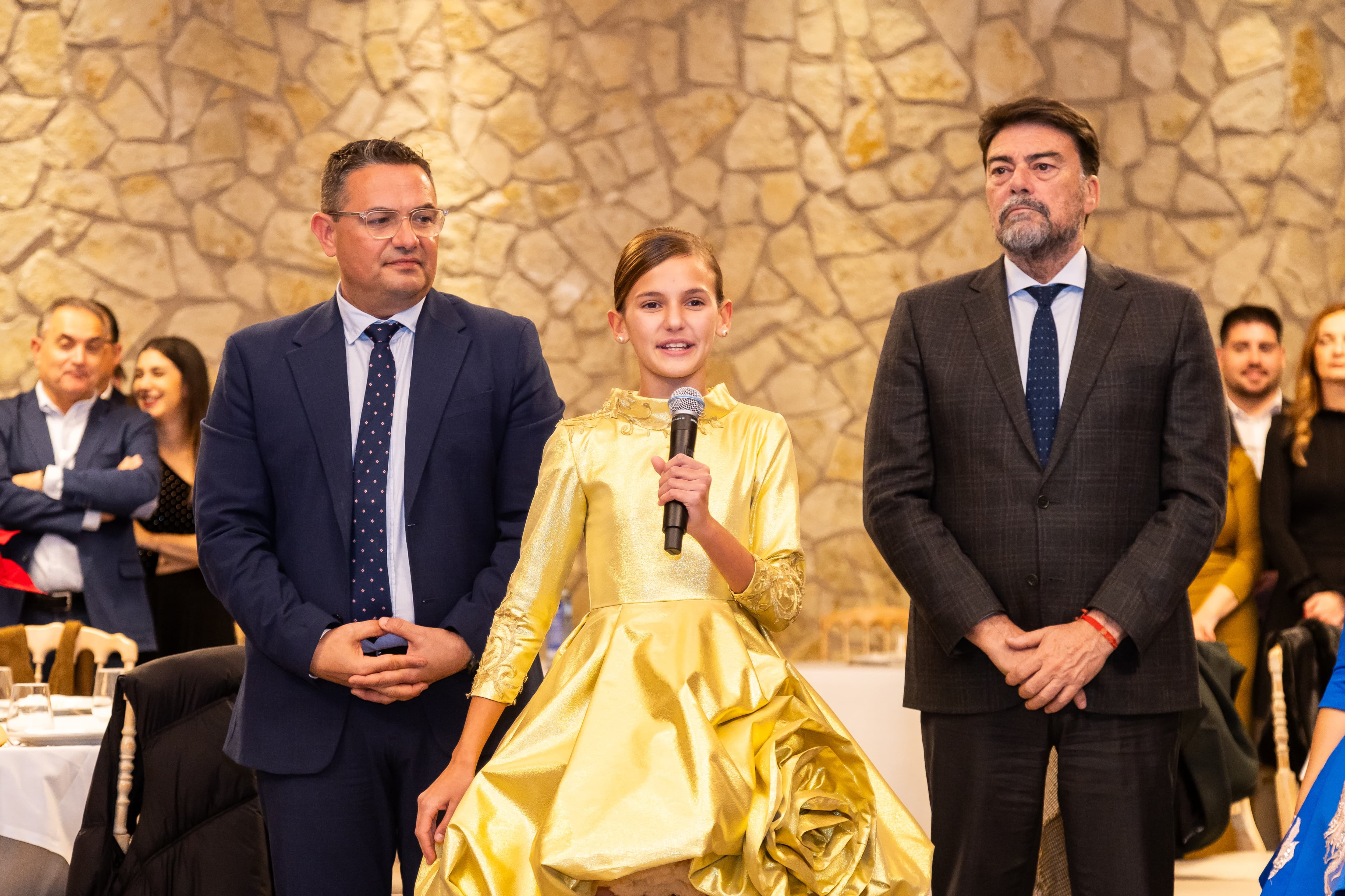 La Bellea del Foc Infantil, Martina Lloret, pronuncia un discurso junto al presidente de la Federació de Fogueres, David Olivares, y el alcalde de Alicante, Luis Barcala. Foto: Ayunamiento de Alicante