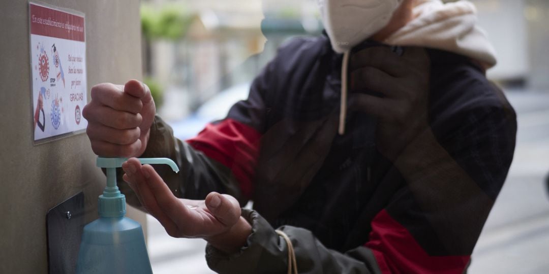 Un hombre se limpia las manos con gel hidroalcohólico antes de entrar a una tienda