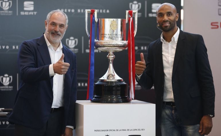 El exjugador de fútbol y ex director deportivo en el F. C. Barcelona Andoni Zubizarreta (i), y el exfutbolista Frédéric Kanouté, pasan con la copa 