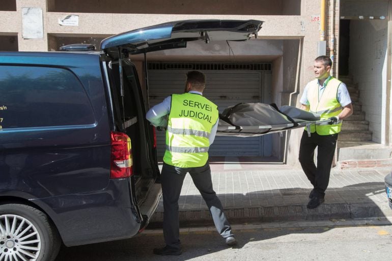 Miembros del servicio judicial retiran el cadáver de la mujer que ha sido asesinada presuntamente por su pareja en su domicilio de Badalona.