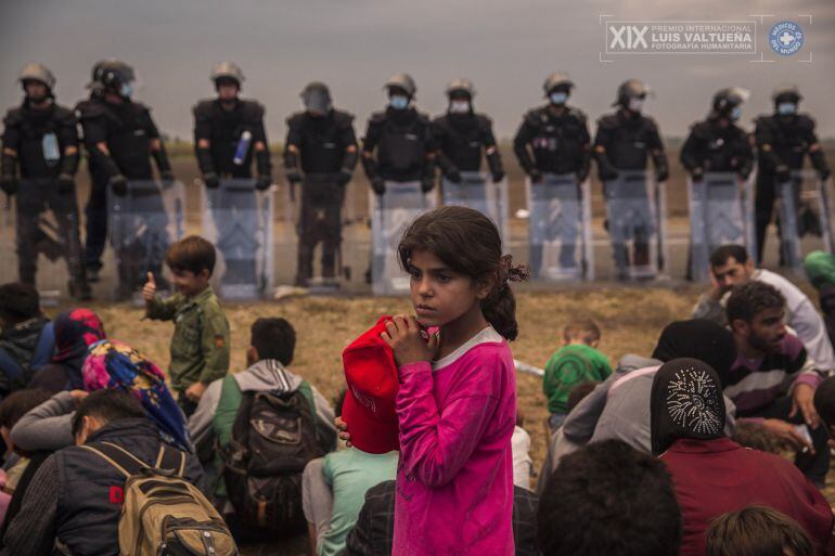 Una niña espera a ser trasladada a un campo de refugiados y refugiadas, junto a cientos de personas en el punto de recepción de Roszke, fronterizo con Serbia.