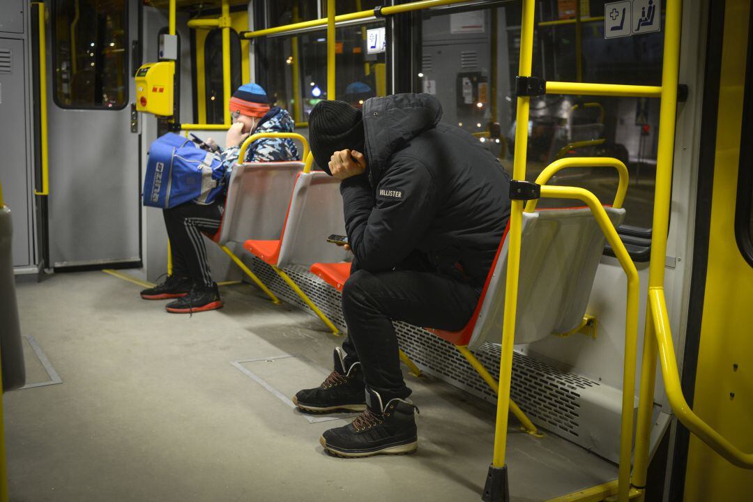 Imagen de un joven mirando el móvil mientras viaja en un autobús