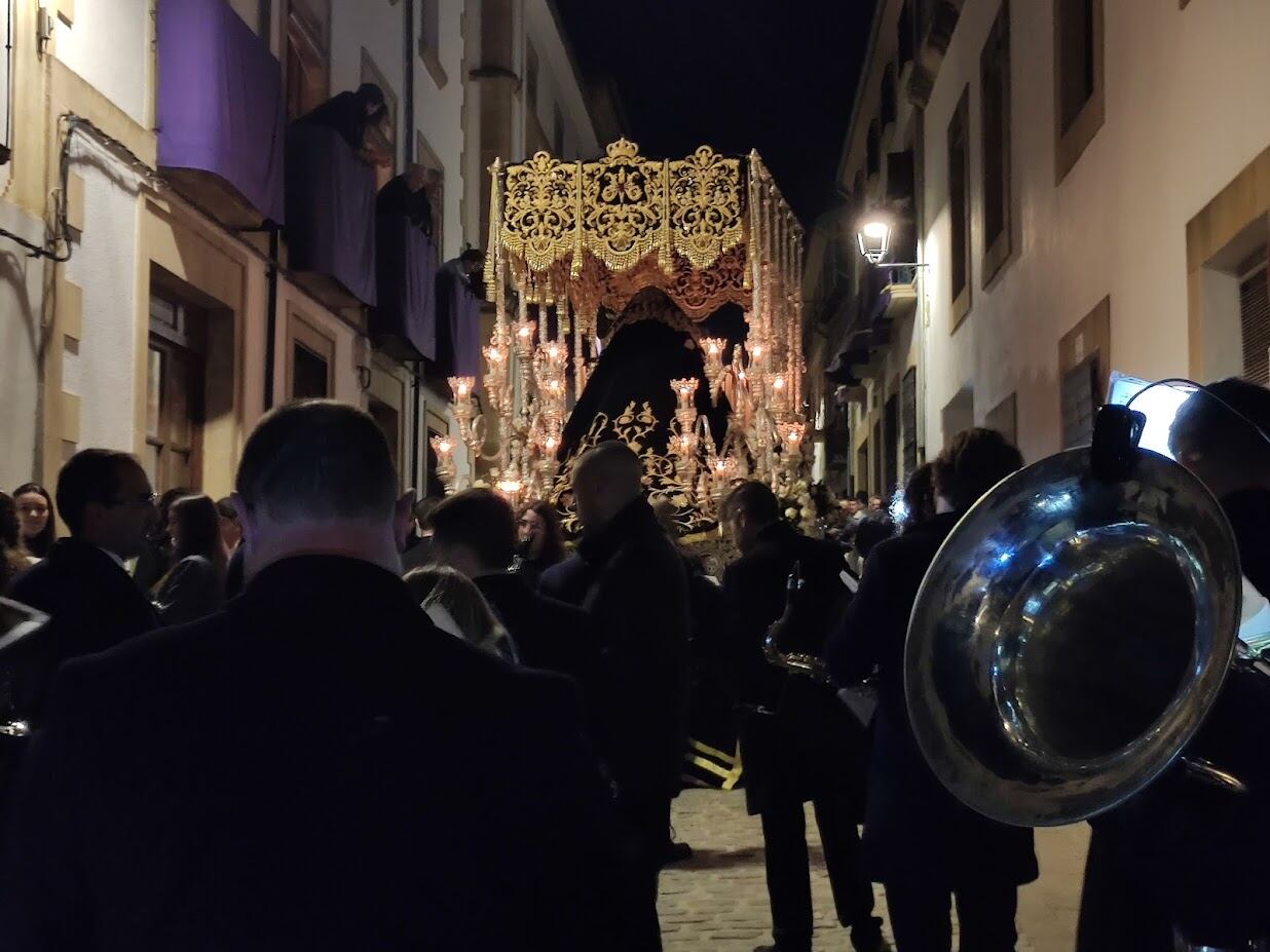 El palio de la Virgen de la Soledad de Baeza alejándose por las calles del centro con una banda de música interpretando marchas de Semana Santa.