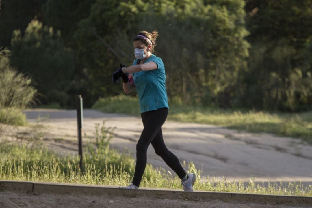 Una mujer corriendo con la mascarilla puesta.