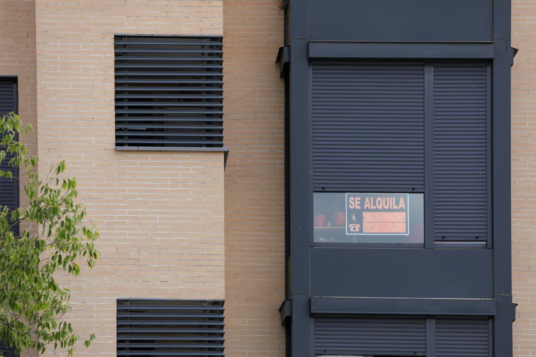 En la fachada de un edificio se ve un cartel de &#039;Se Alquila&#039; bajo la persiana de uno de los pisos.