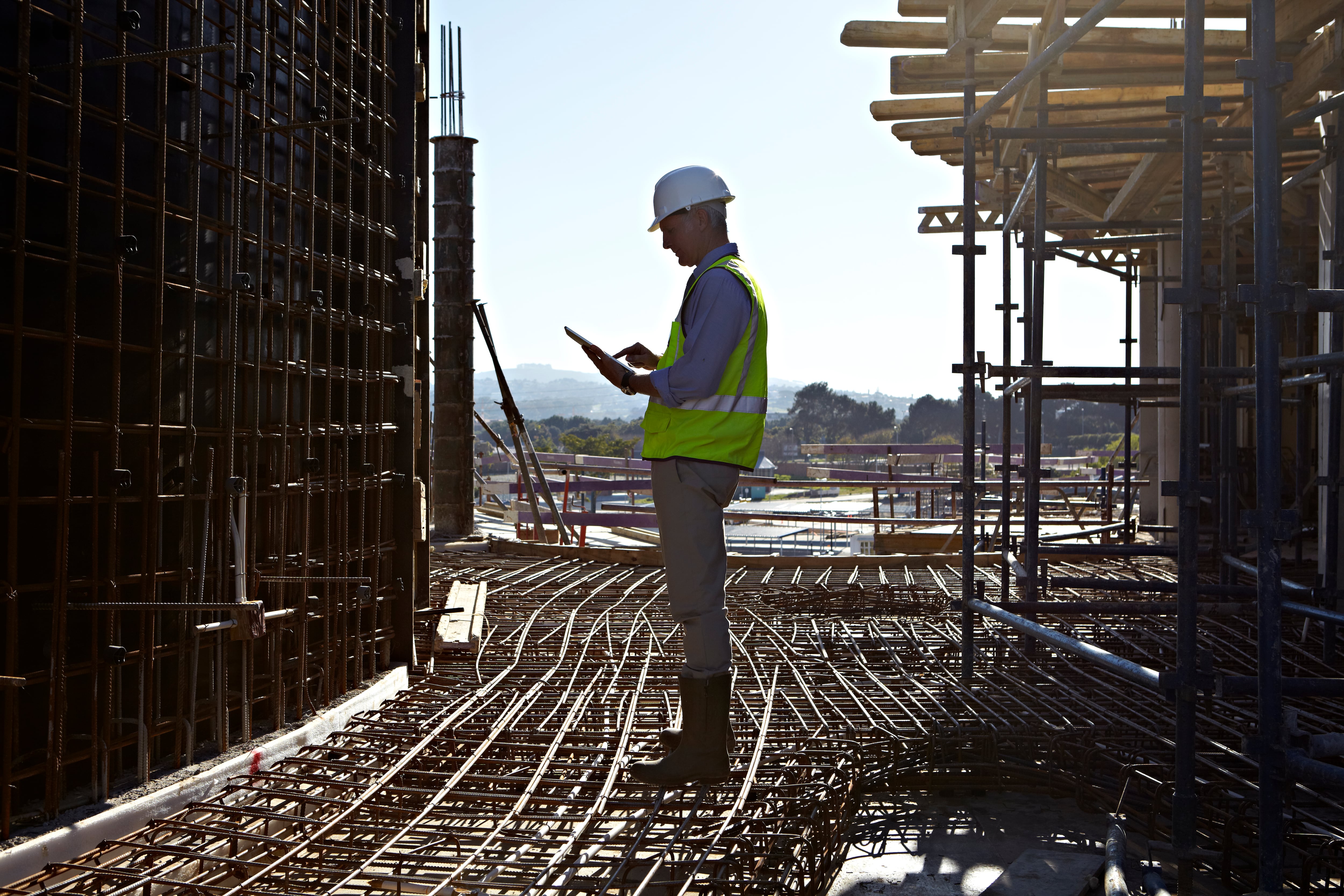 Un arquitecto consulta su dispositivo electrónico en unas obras