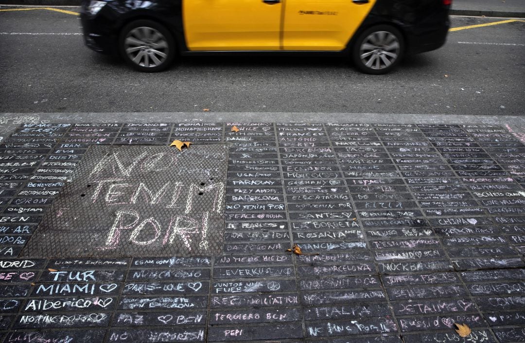 Un taxi pasa junto a los mensajes de apoyo escritos con tiza en una acera de Las Ramblas de Barcelona dos días después de los atentados.