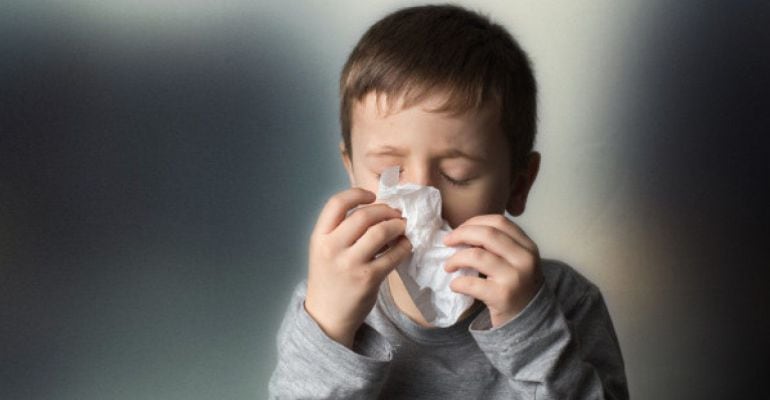 Un niño se suena la nariz con un pañuelo de papel.