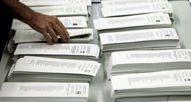 Un ciudadano coge una papeleta de una cabina en un colegio electoral.