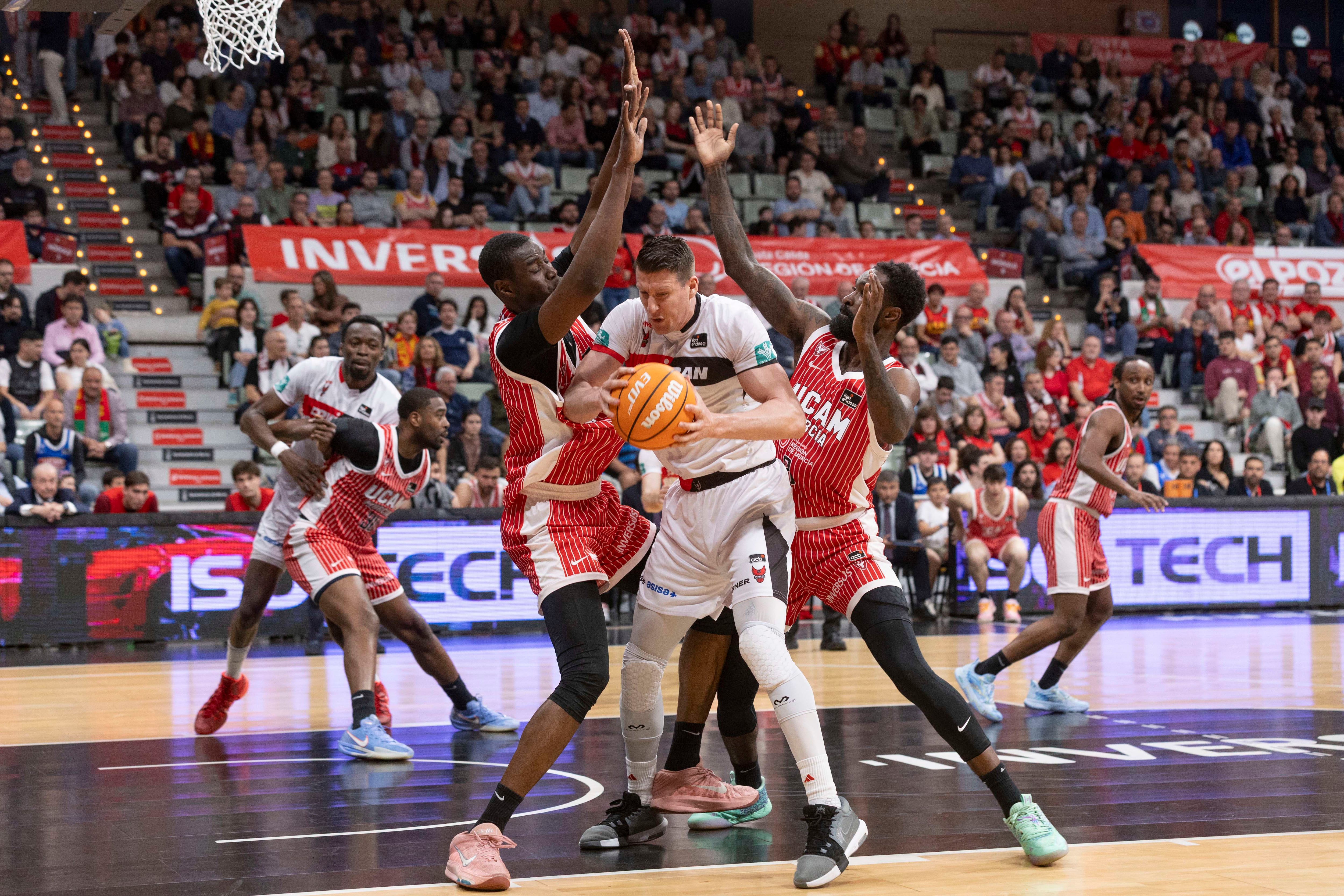 El ala pívot croata de Coviran Granada Luka Bozic controla el balón ante la presión del pívot de UCAM Murcia Diagne y del ala pívot cubano Howard Sant- Roos, durante el partido de la vigésima sexta jornada de la Liga Endesa que están disputando este domingo en el Palacio de los Deportes de Murcia. EFE/Marcial Guillén