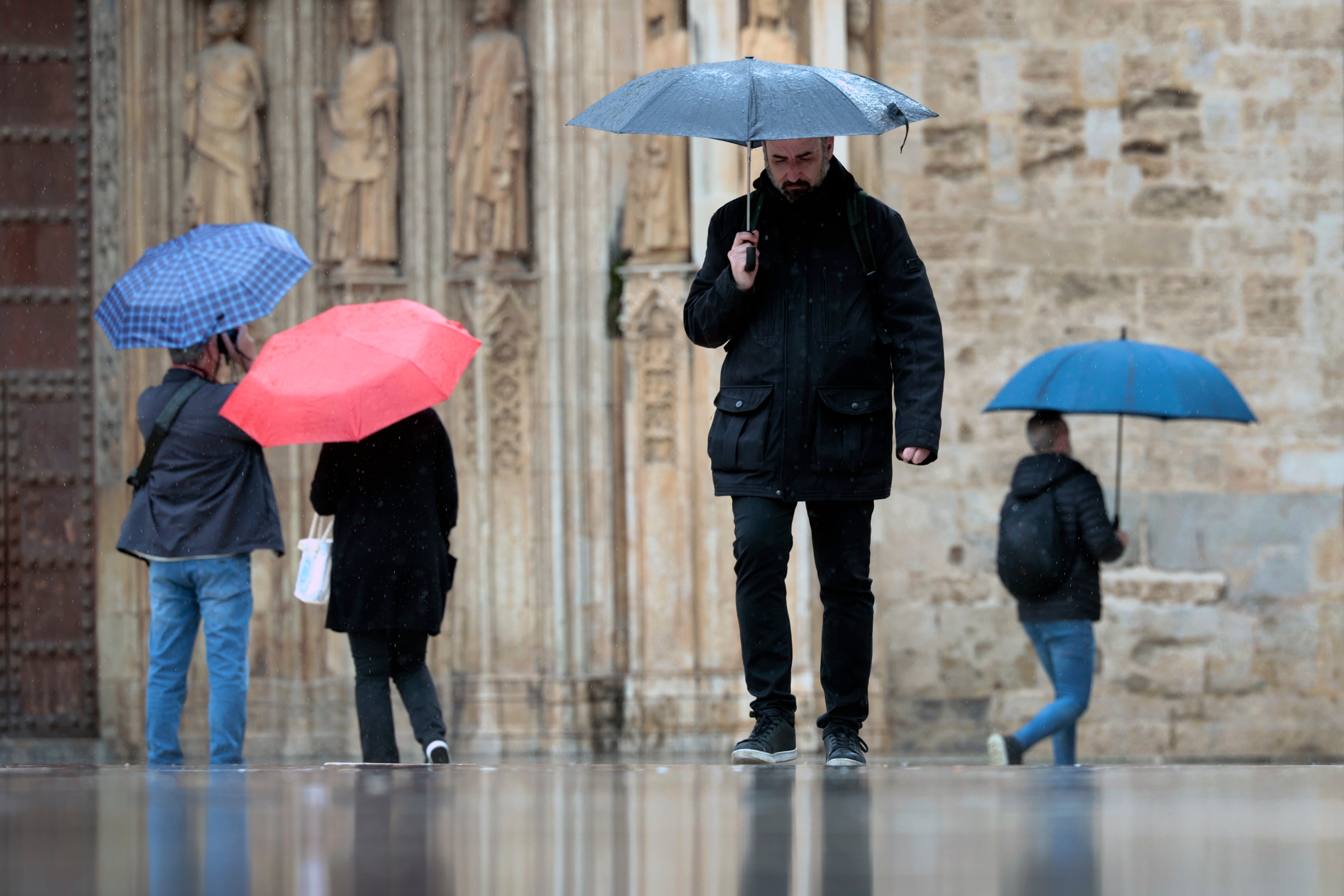 Varias personas pasean bajo la lluvia.