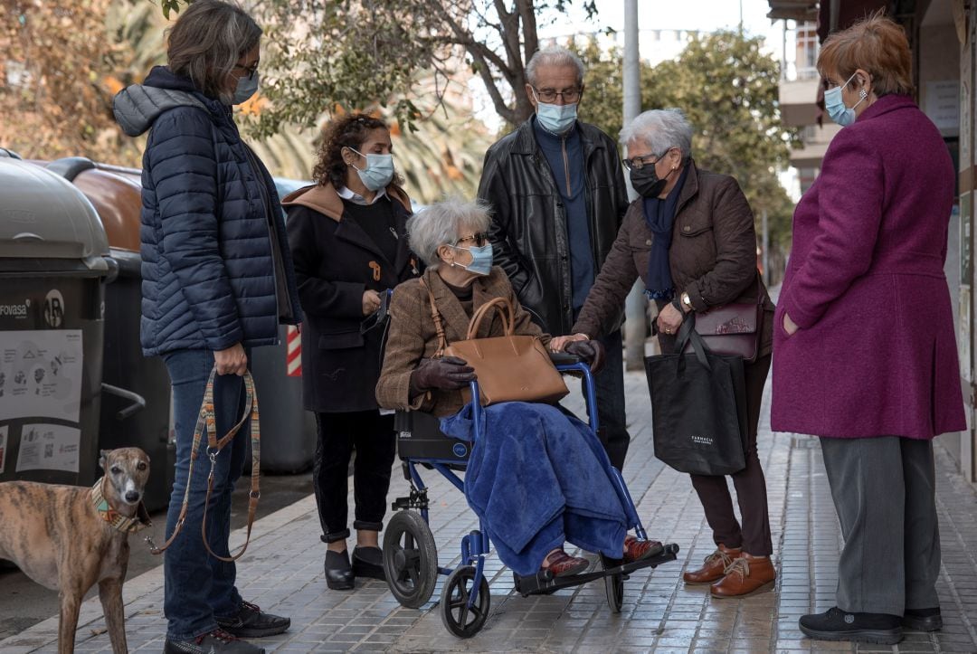 María (3i) conversa con una vecina (2d), durante un paseo con su hija Noelia (i), su marido José (3d), su cuñada Pili (d), y su asistenta Elisa (2i). María tenía 68 años cuando la semana pasada murió en València por eutanasia, el recurso sanitario y legal al que se aferró para dejar de sufrir. 