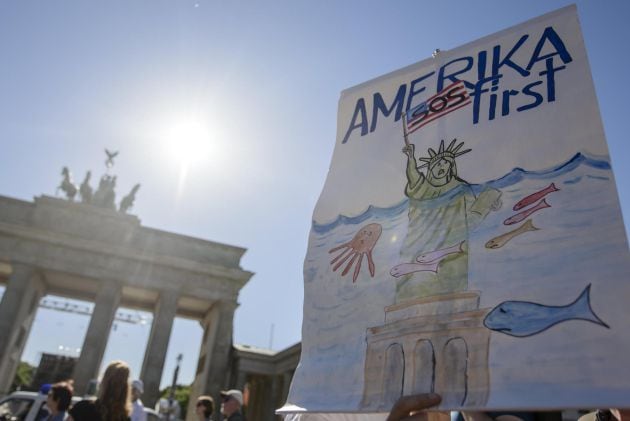 Un manifestante sostiene un cartel en el que se lee &#039;America SOS primero&#039;, durante las protestas contra la salida de Estados Unidos del Acuerdo de París