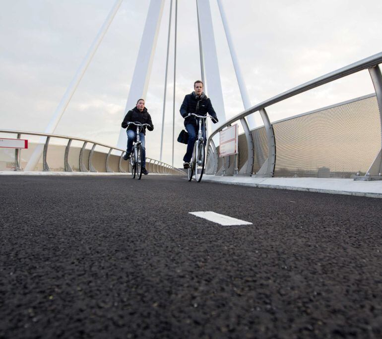 Dos ciclistas pasan por el puente para bicicletas 'The Snelbinder' hoy, martes 19 de enero de 2016, en Naaldwijk, Holanda. El puente, es el primero en Holanda, con un tipo especial de asfalto que contiene varias sales que al contacto con la lluv