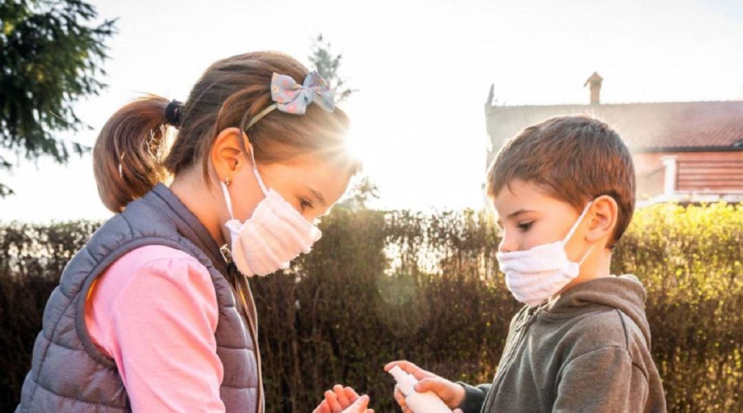 Niños con mascarilla se lavan con gel hidroalcohólico.