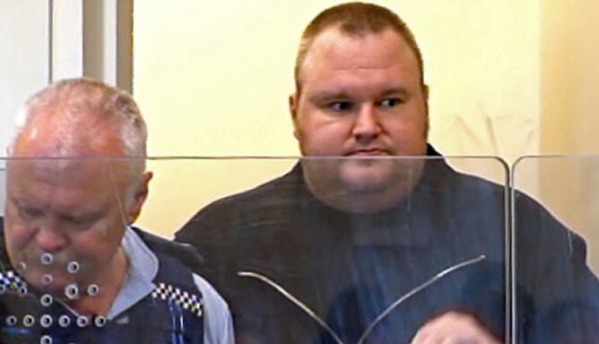 El fundador de Megaupload, Kim Schmitz, escoltado por un policía en los juzgados de Auckland (Nueva Zelanda)