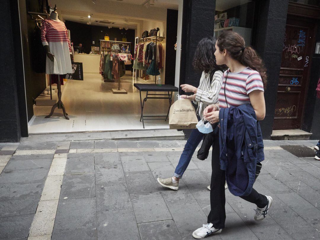 Dos jóvenes pasan por la puerta de una tienda de ropa en Pamplona