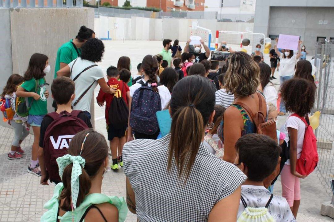  Alumnos acompañados por sus padres en la entrada de un colegio.
