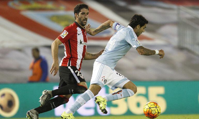 El centrocampista argentino del Celta de Vigo Augusto Fernández (d) se escapa de Raúl García, del Athletic Club, en el partido de Liga, correspondiente a la decimoséptima jornada en Primera División, que se disputa esta noche en el estadio de Balaídos, en Vigo
