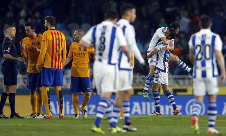 Los jugadores de la Real celebran la victoria, mientras los del Barça protestan al árbitro