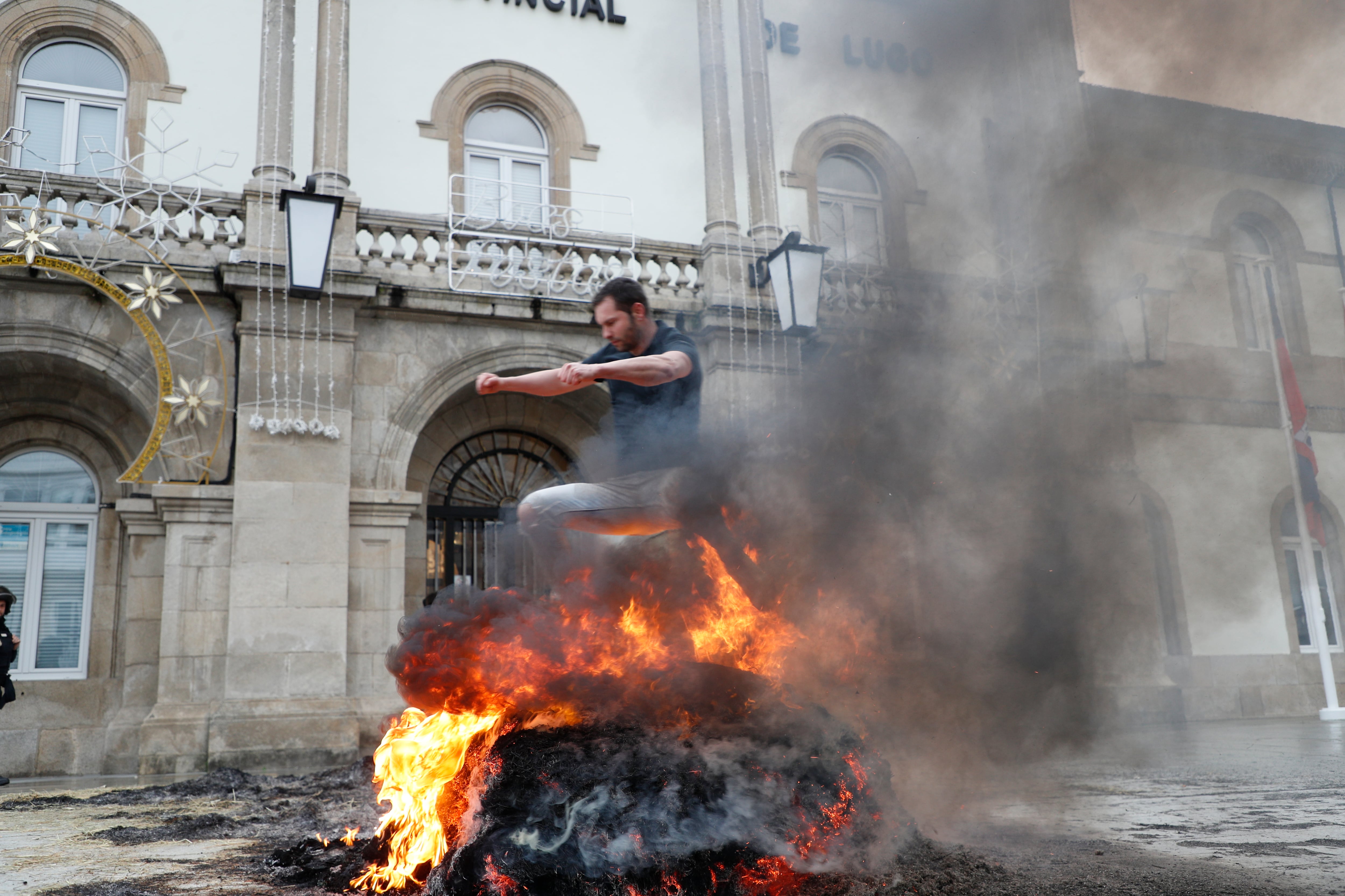 LUGO, 14/01/2026.-Quema de paja a las puertas de la Diputación Provincial de Lugo durante la protesta de agricultores contra el tratado comercial de la Unión Europea con Mercosur. Por segundo día consecutivo, decenas de tractores volvieron a provocar este martes retenciones y atascos en el centro de Lugo, con motivo de esa protesta convocada por las organizaciones Agromuralla -que agrupa a productores de leche de las provincias de Lugo y A Coruña- y Gandeiros Galegos da Suprema -ganaderos que producen carne de Ternera Gallega Suprema-. EFE/ Pedro Eliseo Agrelo Trigo