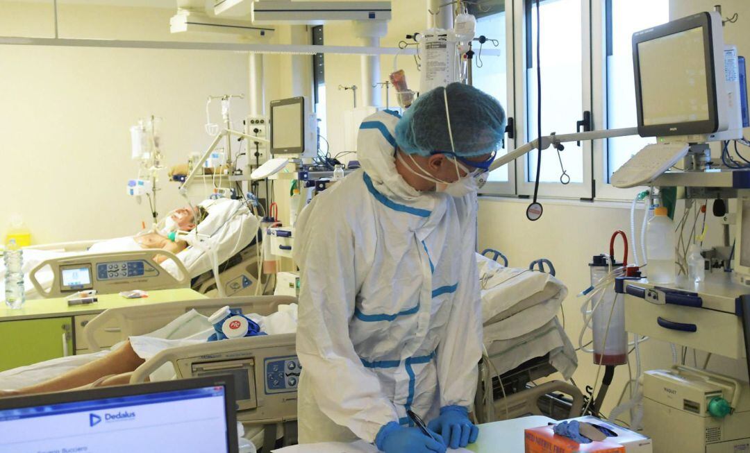 Un profesional sanitario trabajando en un hospital con dos afectados por coronavirus.