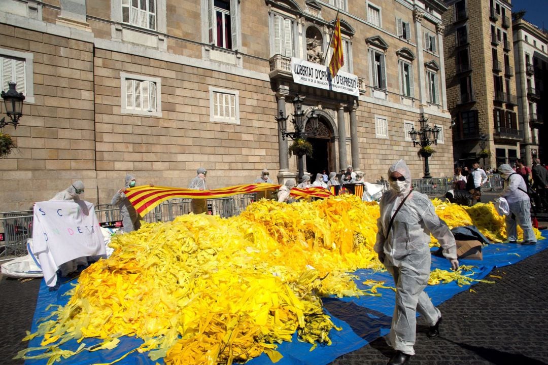 Miembros de la brigada de limpieza d&#039;Els Segadors del Maresme, que se dedican a quitar lazos amarillos de lugares públicos, los depositan frente a la fachada principal del Palau de la Generalitat.