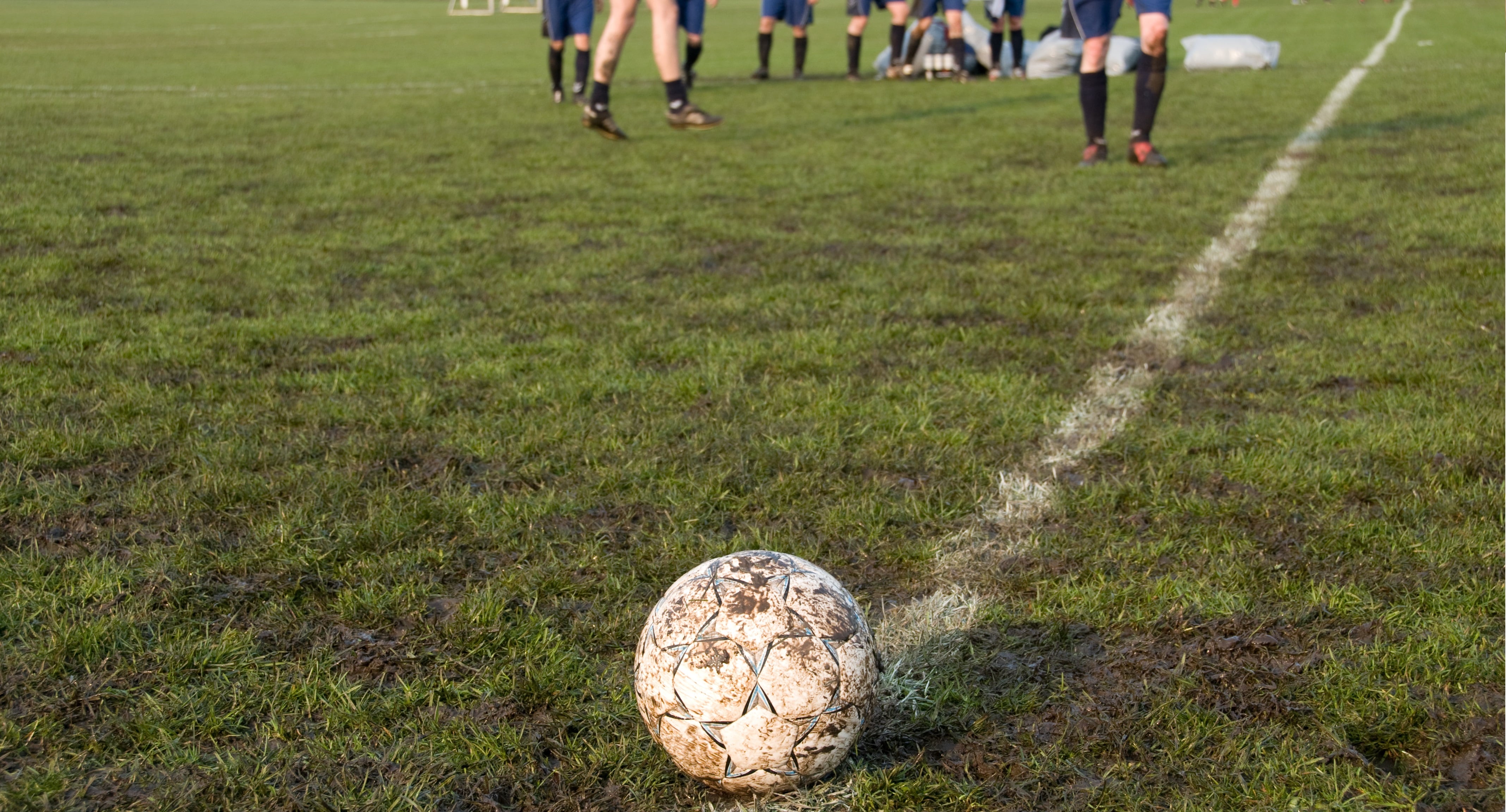 Soccer ball in focus. Soccer team in the background. 