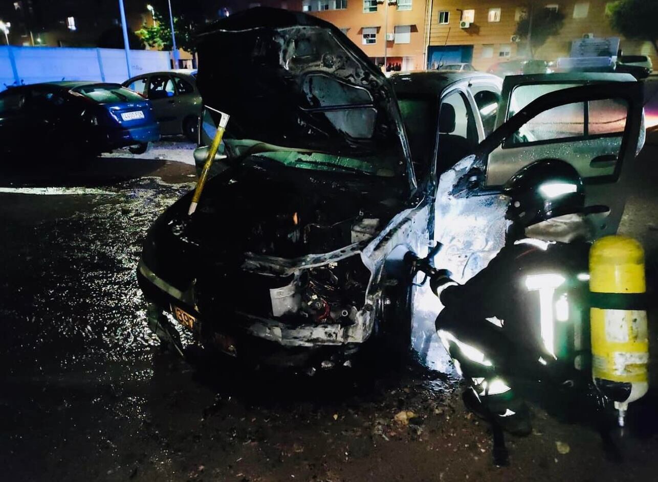 Un bombero sofoca las llamas en un vehículo aparcado frente al centro de Salud del Bulevar, en Jaén.