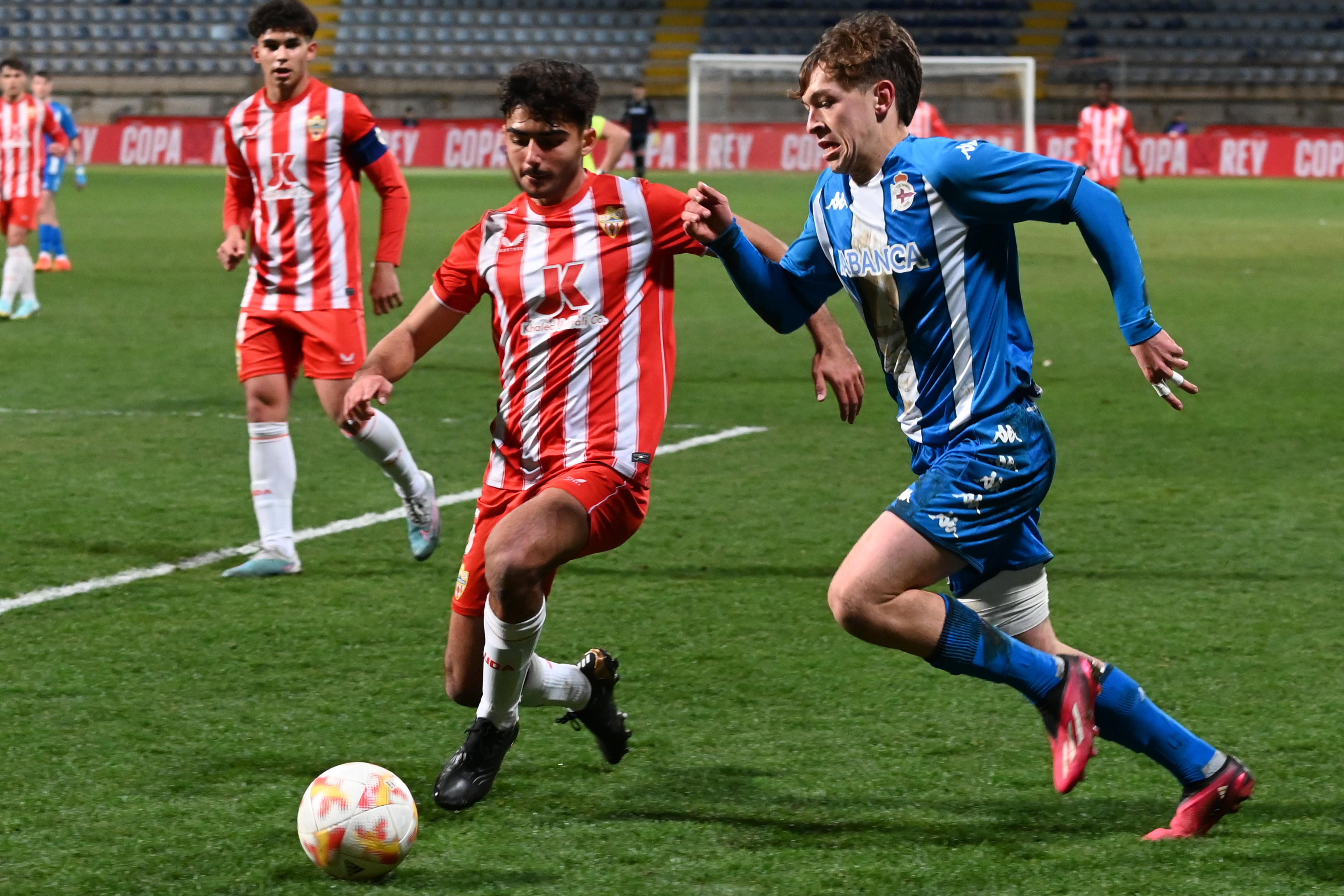 LEÓN, 07/03/23. El defensa del Almería Sub19 Edu Pla (c) disputa un balón con el atacante del Deportivo Sub 19 durante el partido de semifinales de la Copa del Rey de Fútbol entre el Deportivo de La Coruña y UD Almería que se disputa este miércoles en el estadio Reino de León. EFE/J.Casares
