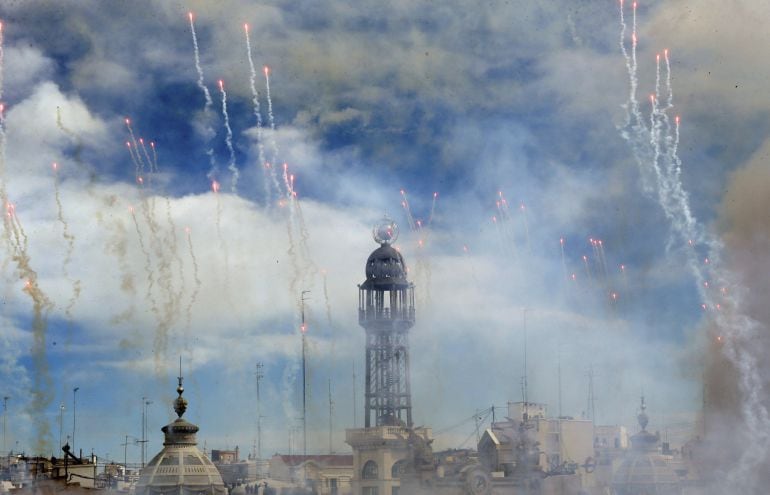 Imagen de la mascletá disparada en la plaza del Ayuntamiento con la torre del Palacio de las Comunicaciones de fondo