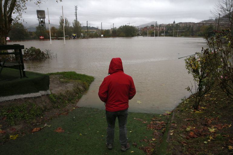 Un hombre observa el campo de rugby de la localidad guipuzcoana de Hernani, totalmente anegado por el desbordamiento del río Urumea.