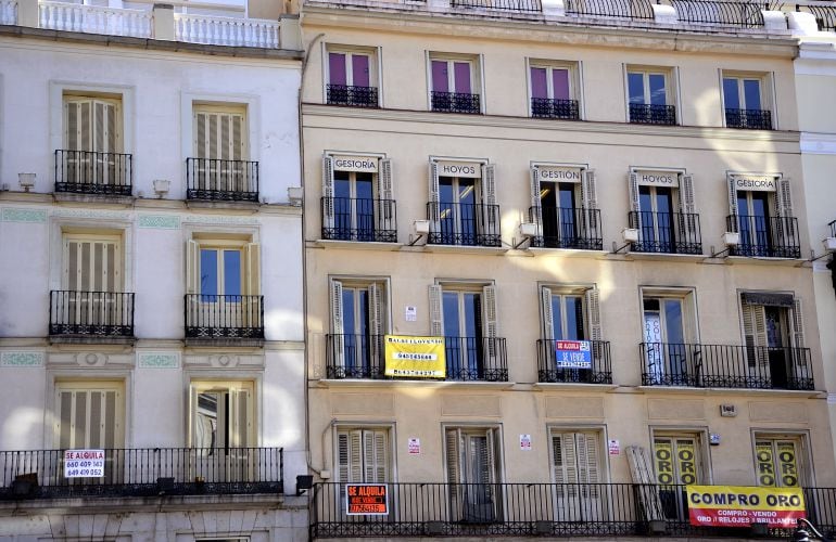 Fachada de un edificio de la capital en la que diferentes carteles de venta y alquiler de pisos 