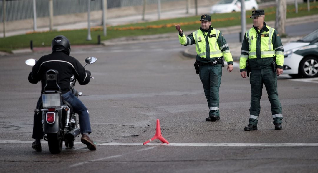 Dos guardias civiles de Tráfico paran a una moto que se encuentra cerca de la entrada del recinto de IFEMA 