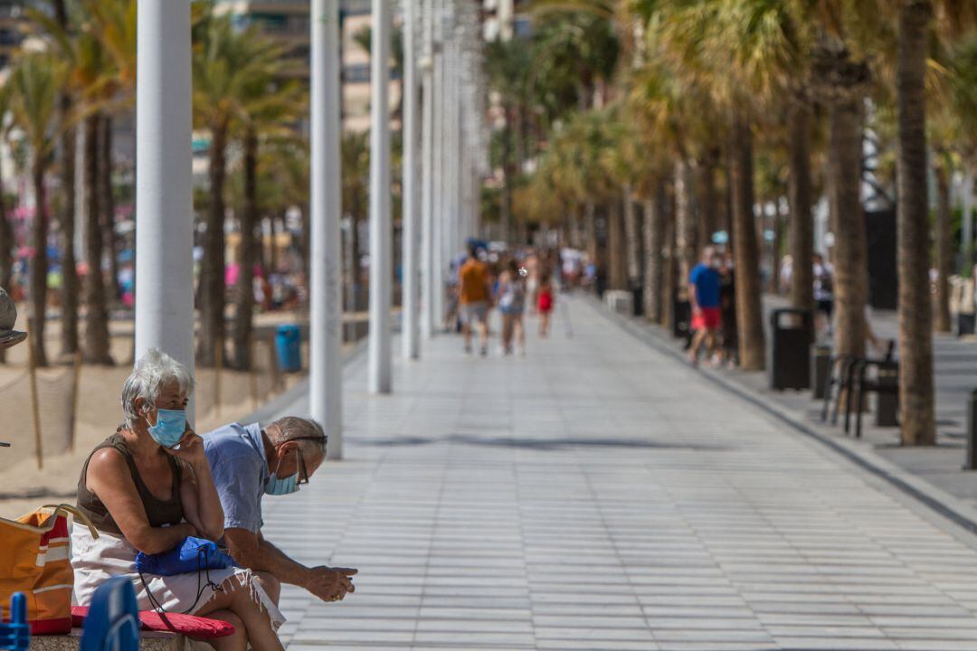 Dos personas descansan en el paseo marítimo de Benidorm