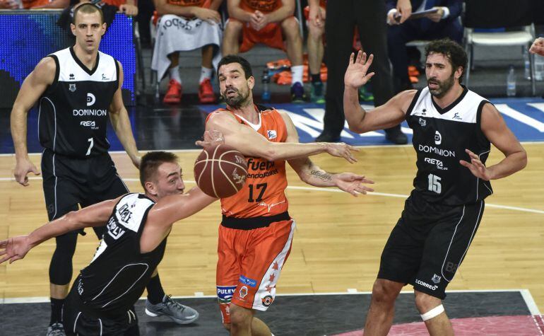 El escolta del Valencia Basket Rafa Martínez (centro) pasa el balón frente al ala-pívot belga Axel Hervelle (izquierda), y los aleros Alex Ruoff (izquierda, atrás) y Álex Mumbrú (derecha), del Dominion Bilbao Basket, durante el partido de la sexta jornada de la Liga ACB que se disputa en el Bilbao Arena.