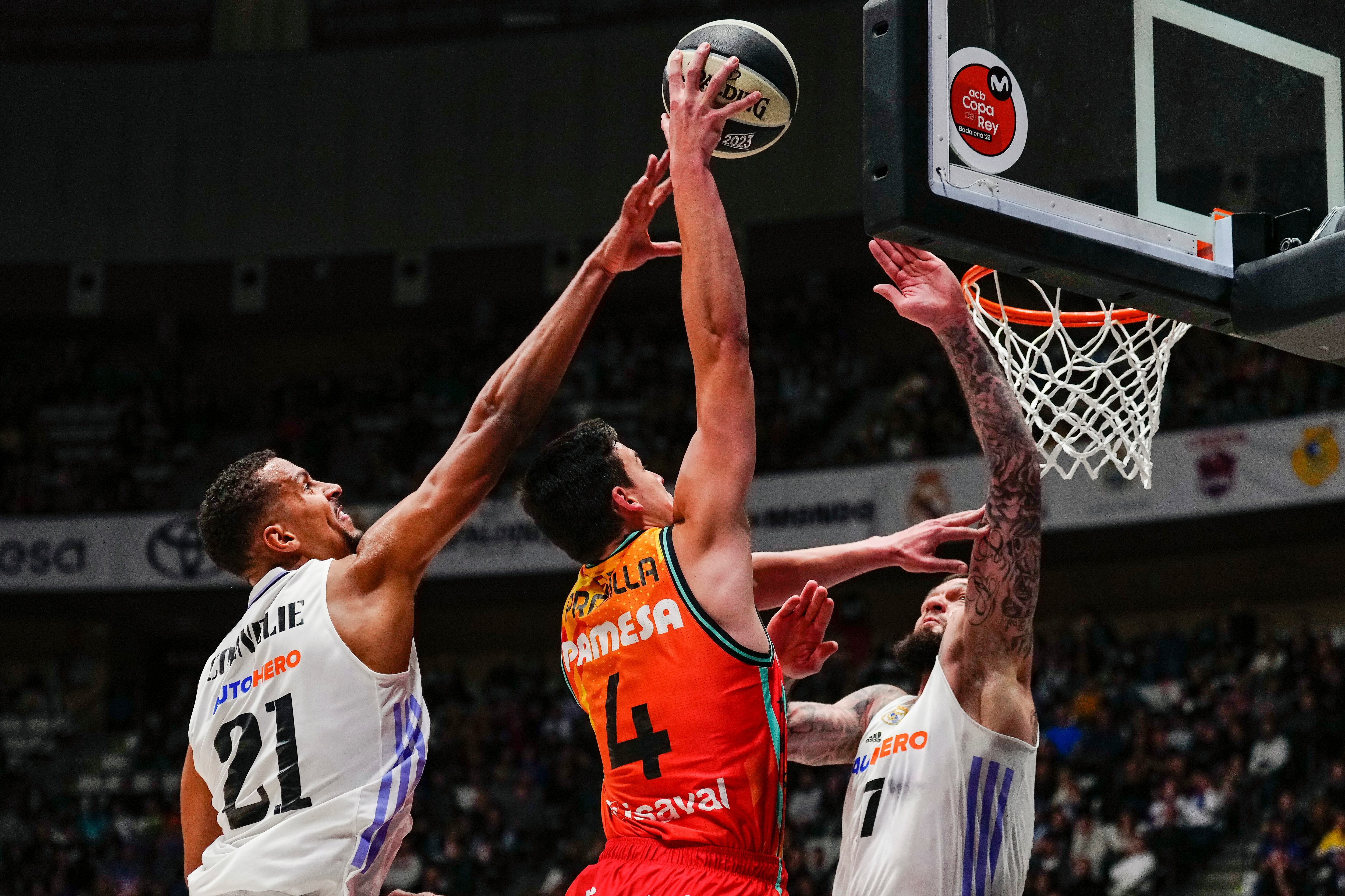 El alero del Valencia Basket Jaime Pradilla, intenta encestar, ante los pívot franceses del Real Madrid Petr Cornelie y Vincent Porier durante el partido correspondiente a cuartos de final de la Copa del Rey de baloncesto que se disputa en el Palau Municipal d&#039;Esports de Badalona. EFE/ Enric Fontcuberta.